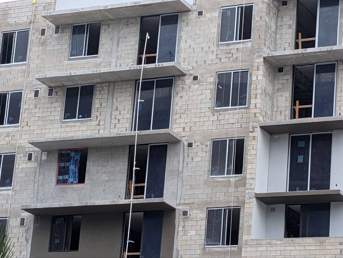 Crews field-painting factory-finished aluminum window frames on a building under construction